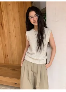 Model wearing a beige sleeveless linen-blend knit top in a natural setting