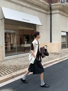 Full shot of women's white PU leather vest jacket in an aesthetic street setting