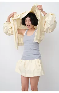 Woman wearing a loose light yellow sun protection jacket and matching skirt