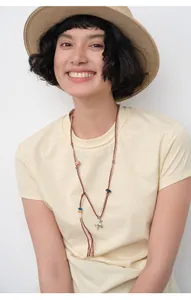 Detail shot of a slim-fit yellow summer T-shirt featuring a unique braided horse pendant necklace.