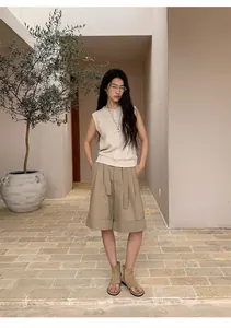 Model wearing a minimalist linen blend sleeveless knitted vest with khaki wide-leg shorts.