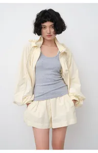 Model wearing a loose pale yellow sun protection jacket and shorts set with grey tank top