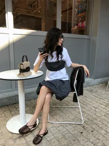 Modella indossa una t-shirt bianca e un set di canotta a righe minimalista all'aperto.