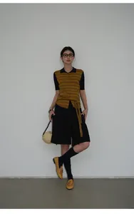 Pantalones cortos negros línea A con un top de rayas y mocasines amarillos.