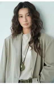 Dettaglio di donna in blazer autunnale beige minimalista e pendente in pietra