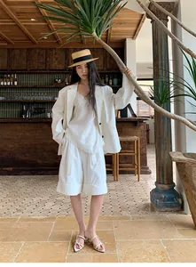 Elegante completo blazer bianco da donna con top in pizzo in un ambiente café tropicale