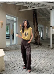 Mannequin portant un t-shirt jaune moutarde imprimé et un pantalon marron large