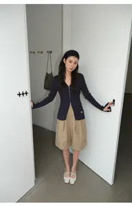 Modelo asiática con pantalones cortos bermuda caqui y cárdigan de punto azul