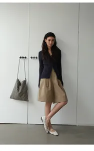 Modelo con pantalones cortos kaki anchos con dobladillo, cárdigan azul y manoletinas.