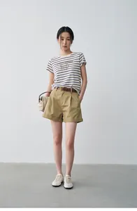 Full-body shot of a model wearing khaki pleated casual shorts with cuffed hems.