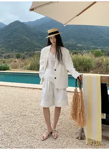 Modella asiatica che indossa un completo blazer bianco minimalista a bordo piscina.