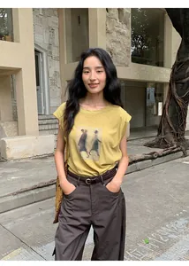 Modèle portant un t-shirt jaune à manches courtes avec imprimé vintage et pantalon marron