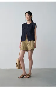 Elegant Asian model posing in minimalist khaki pleated cuffed shorts for summer