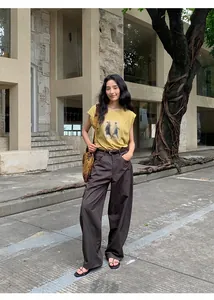 Vue complète d'une femme portant un t-shirt graphique jaune et un pantalon large