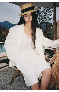 Modella indossa un blazer bianco minimalista in stile coreano in un resort all'aperto