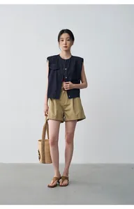 Elegant women's khaki pleated shorts with rolled hem styled with a dark navy denim vest