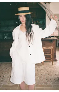 Modella indossa un blazer bianco oversize e un top in pizzo in un interno editoriale.