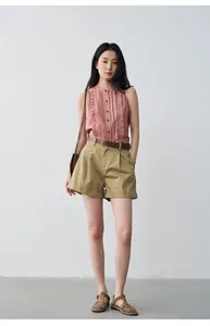 Detail view of high-waisted khaki pleated shorts with rolled cuffs for a casual look.