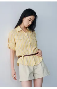 Detail view of women's mid-waist pleated shorts with cuffed hem in a summer beige style