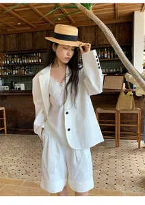 Elegante completo blazer e pantaloncini bianchi in stile coreano per donna in un caffè