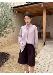 Mujer elegante con pantalones cortos evasé con vuelta y blusa malva en un jardín.