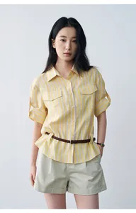 Detailed view of casual beige rolled-up shorts and yellow striped shirt on model