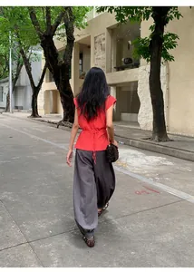 Vue de dos d'une femme portant un top rouge à petites manches et un pantalon gris.
