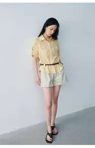 Full body view of a woman wearing beige pleated mid-waist shorts and a striped shirt