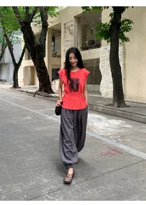Look urbain d'une femme portant un t-shirt rouge à manches courtes et un pantalon large gris