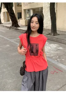 Photo de rue d'une femme portant un t-shirt rouge à manches courtes avec imprimé.