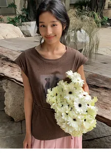 Détail d'un t-shirt marron sans manches pour femme avec imprimé vintage et manches volantes.