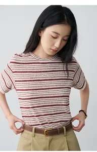 Primer plano de una camiseta de lino de rayas rojas con puños de encaje y bordados.