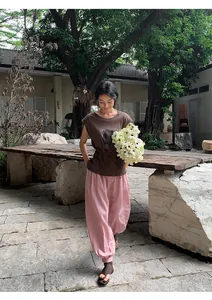 Détail visuel d'une femme portant un t-shirt marron à manches courtes dans un jardin fleuri
