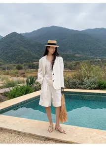 Elegante conjunto de pantalón corto y blazer blanco junto a una piscina y montaña