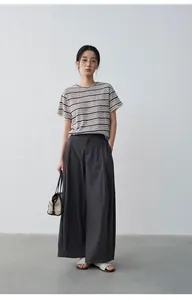 Vista de cuerpo entero de una mujer con camiseta de lino a rayas y pantalón ancho gris
