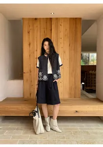 Mujer elegante con pantalones cortos de verano línea A y chaleco azul marino bordado