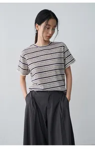 Detalle de una camiseta de lino a rayas para mujer con puños de encaje y bordados finos.
