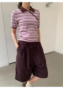 Modelo con pantalones cortos anchos con vuelta marrón oscuro y polo de rayas