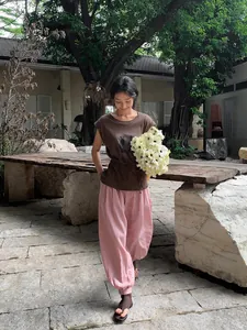 Mannequin asiatique en t-shirt marron imprimé et pantalon rose dans une cour