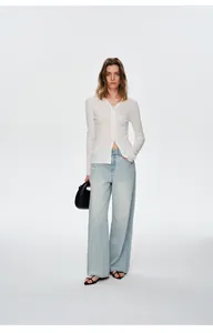 Volledig zicht op wit geribbeld vest met V-hals en een lichtblauwe jeans met wijde pijpen
