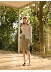 Model draagt een slim-fit V-hals ribgebreid vest en een olijfgroene denim rok.
