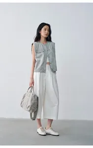 Vista intera di una modella con gilet di jeans grigio ampio e pantaloni bianchi a gamba larga