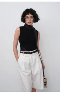 Vue complète d'une femme en bermuda plissé blanc au style estival et minimaliste