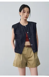 Gilet di jeans blu scuro senza maniche con scollo rotondo, abbinato a shorts kaki.