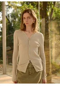 Elegante beige nauwsluitende gebreide cardigan met V-hals getoond op een model bij zonlicht