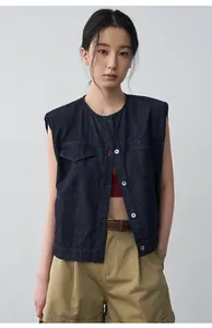 Dettaglio di un gilet di jeans blu scuro ampio con cuciture rosse a contrasto