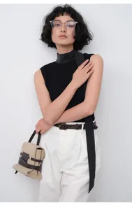 Mannequin asiatique portant un haut noir minimaliste et un pantalon blanc chic
