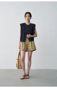 Stile alla moda di un gilet in denim blu scuro abbinato a pantaloncini color kaki.