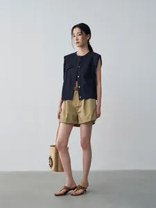 Modella indossa gilet di jeans blu scuro senza maniche con pantaloncini kaki