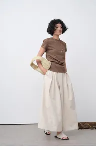 Asian model wearing a brown slim fit T-shirt and cream pleated wide-leg trousers ensemble
